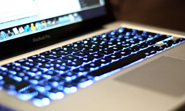 The keys of a Mac brand laptop glow with blue light