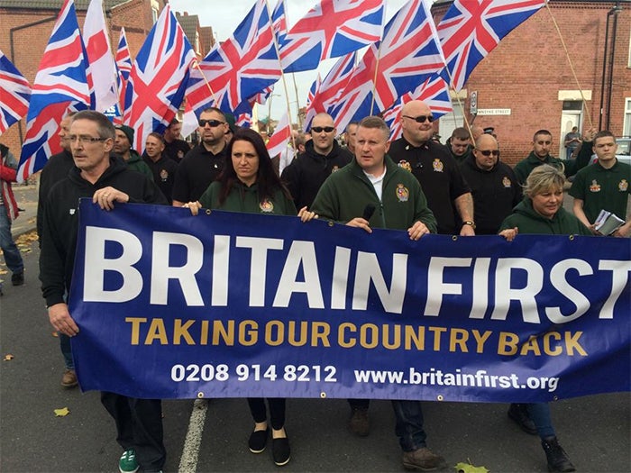 Demonstrators gather at a "Britain First" rally. Their sign reads "Britain First: Taking Our Country Back."