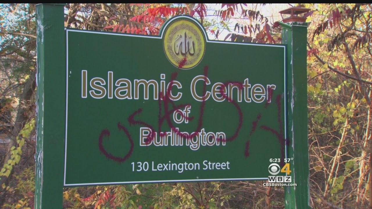 A sign that reads "Islamic Center of Burlington" is defaced by graffiti that reads "USA USA" in large red letters.