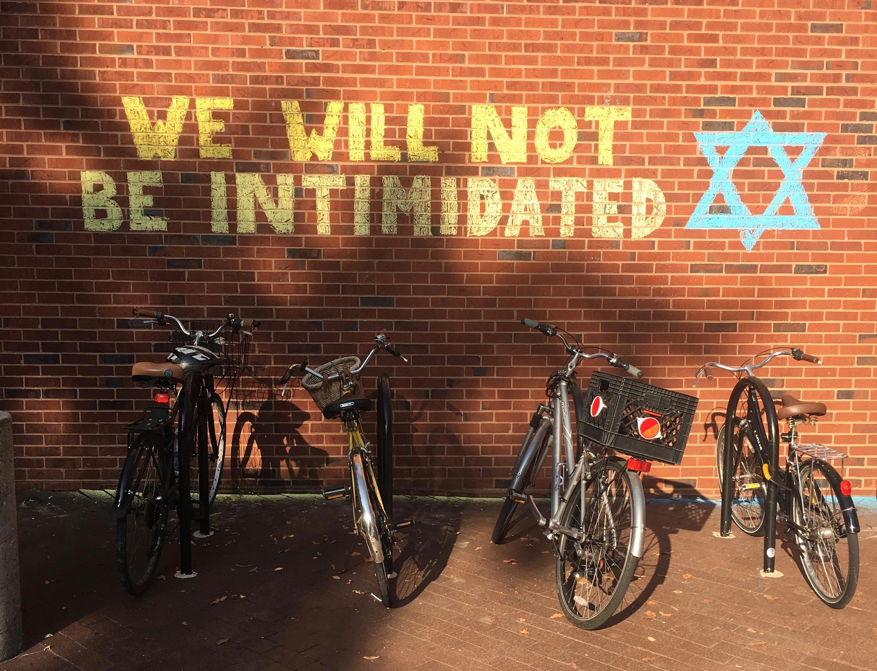 The words "We will not be intimidated" is written in chalk next to a Star of David on a red brick wall