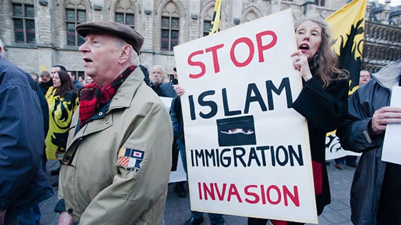 At a protest in Belgium, a women carries a sign that reads "Stop Islam Immigration Invasion."