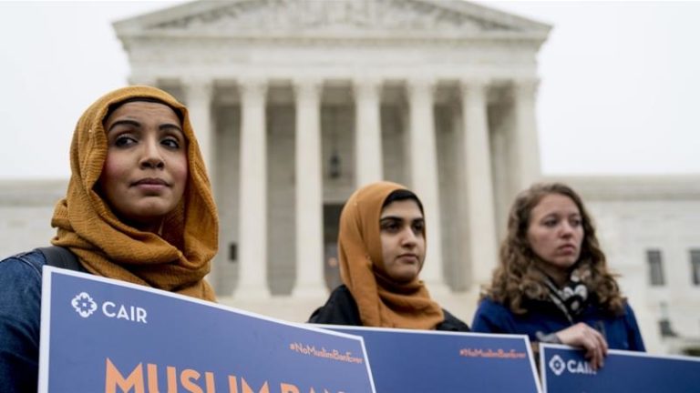 three figures in front of the US Supreme Court holding banners