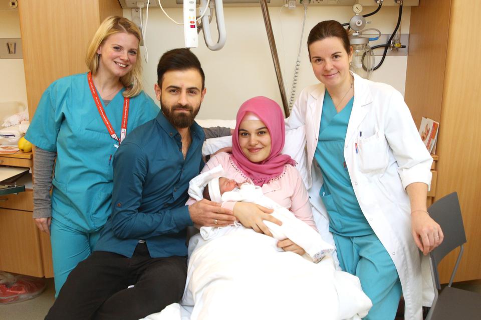 Newborn Asel Tamga, the first baby born in Austria in 2018, is pictured with her parents and two nurses in a hospital room.