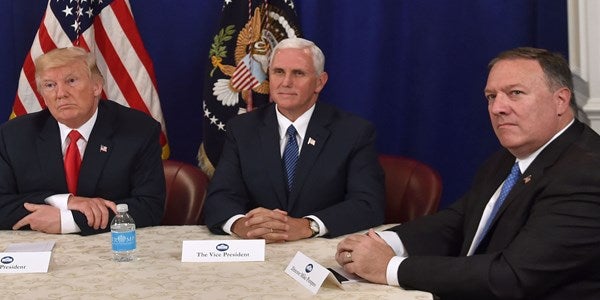Donald Trump, Mike Pence, and Mike Pompeo are pictured sitting around a table.