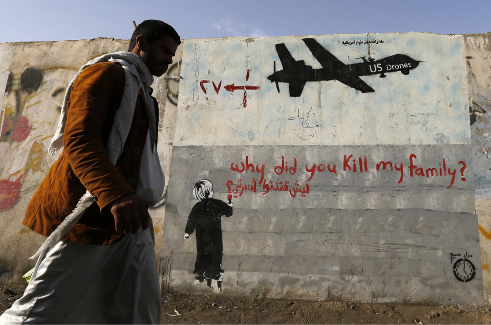 A man walks past a graffiti, denouncing strikes by U.S. drones in Yemen, painted on a wall in Sanaa November 13, 2014