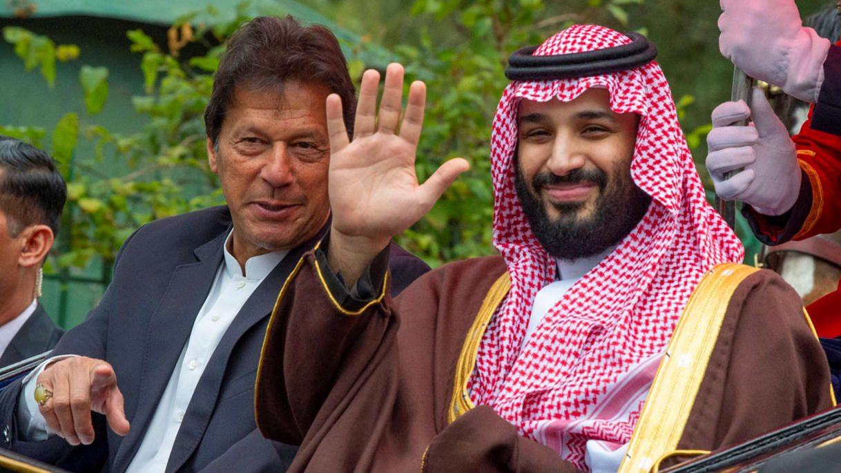 Portrait of two men, Imran and MBS, with figure on the right raising a hand while the figure on the left looks on