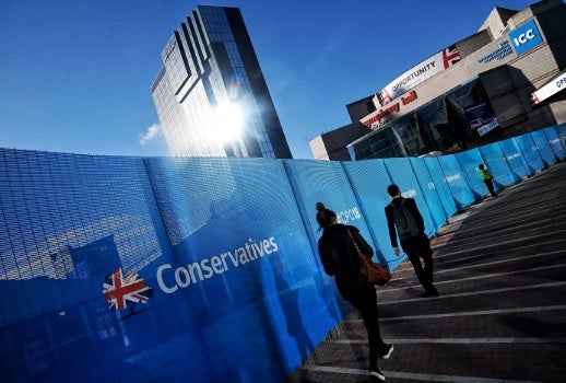 Two figures walk up steps bordered by the British flag that says "Conservatives"