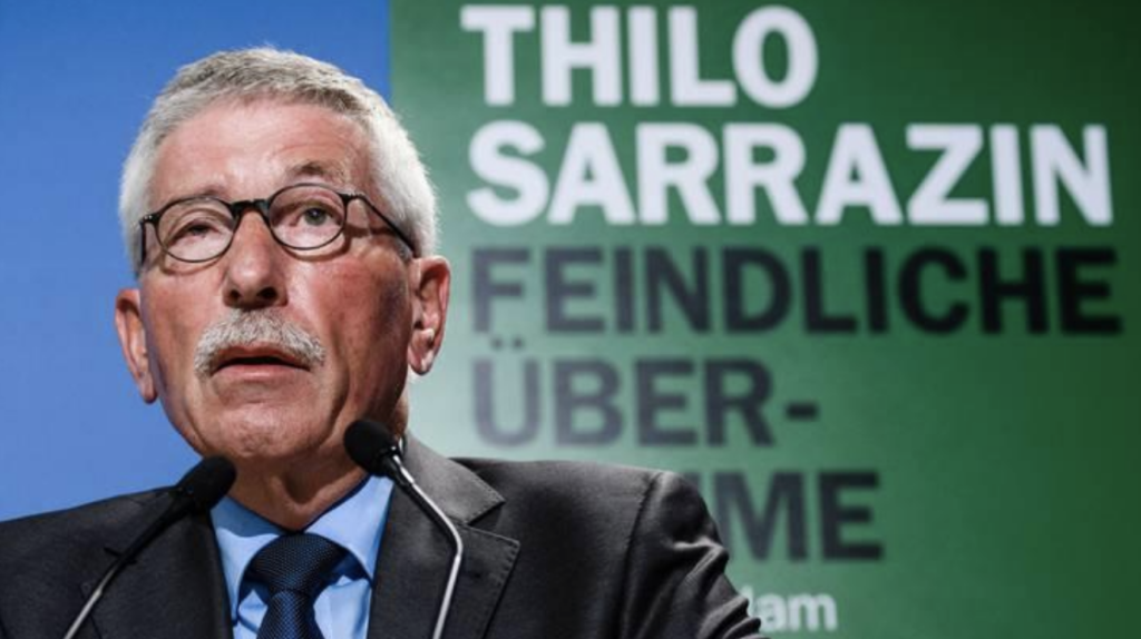 The featured image of this article is of Sarrazin, speaking at a Press Conference